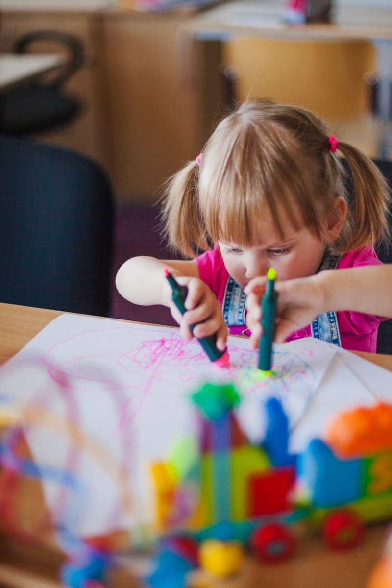 Mädchen zeichnet begeistert mit Filzstiften im Kindergarten